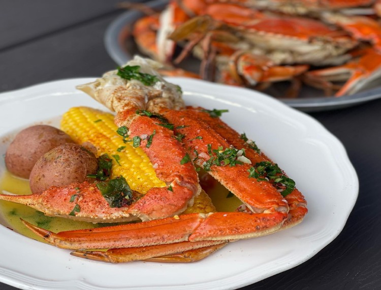 A plate of crabs, potatoes and corn on a table.