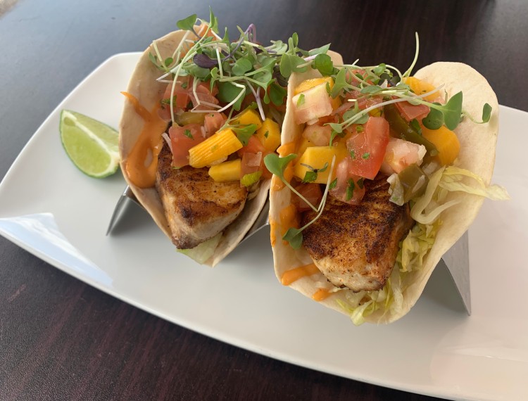 Two fish tacos on a white plate.