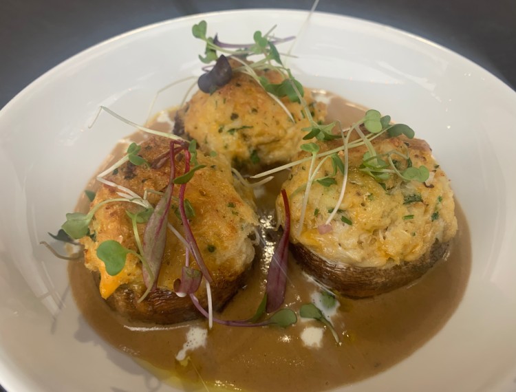 Three stuffed potatoes on a plate with gravy.